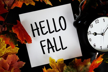 Poster - Hello Fall text with alarm clock and maple leaf decoration on wooden background