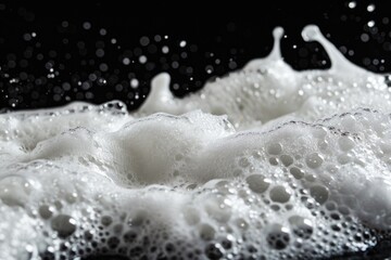 Poster - Close-up shot of foamy water on a black surface, perfect for use in beauty or chemistry-related contexts