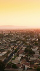 Wall Mural - Lovely scenery of a usual city in United States. Straight quarters of residential area with plain streets and lots of cars at the roadside. Yellow sky at backdrop. Vertical video