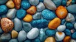 © Dulemegapixel - A collection of assorted colorful stones, including blue, orange, and grey ones, displayed in a neat and organized pattern, symbolizing unity and diversity in nature's beauty.