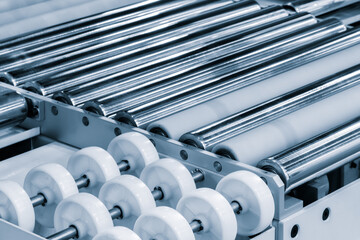 Poster - A conveyor belt with many white wheels on it. The conveyor belt is made of metal and is very long