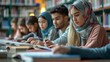 © acnaleksy - University students sitting together at table with books and laptop. Happy young people doing group study in library.