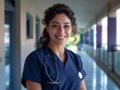 © mirifadapt - smiling beautiful young nurse with dark curly hair wearing uniform, looking at camera, hospital background