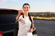 © New Africa - Happy young woman with key near her new car outdoors