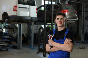 Poster - Young auto mechanic with wrenches at automobile repair shop