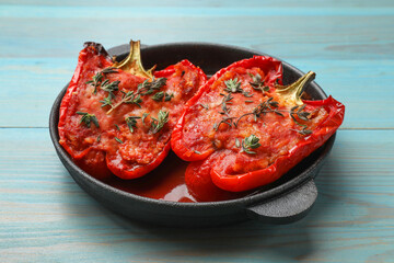 Wall Mural - Tasty stuffed peppers in dish on light blue wooden table