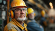 © khonkangrua - An older industrial worker wearing safety gear, including a hard hat, goggles, and earmuffs, representing experience and safety in the workplace.