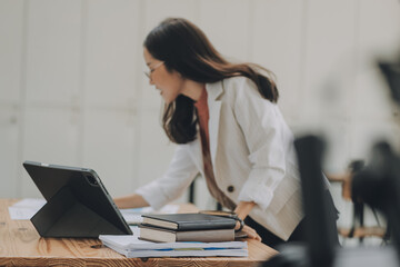 Wall Mural - Happy young asian businesswoman sitting on her workplace in the office. Young woman working at laptop in the office.