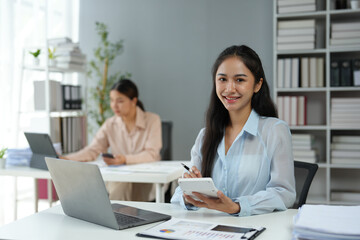 Wall Mural - Asian businesswoman works on laptop and calculates with financial calculator from graphs, statistics, charts. Planning. Business success results in modern office.