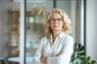 © Ольга Лукьяненко - Business concept. Portrait of middle aged businesswoman ceo standing in office with arms crossed