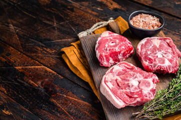 Wall Mural - Fresh Raw lamb neck meat with bone on a wooden board with herbs. Wooden background. Top view. Copy space