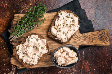 Wall Mural - Cod Liver open Sandwich on wooden board. Dark background. Top view