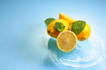 Wall Mural - Juicy lemons with mint on a blue background with water splashes.