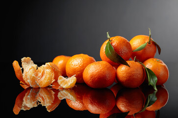 Wall Mural - Tangerines or clementines with green leaves on a black background.