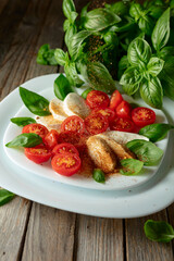 Wall Mural - Mozzarella with basil and cherry tomatoes sprinkled with Mediterranean spices.