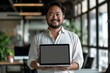 © Elmira - A successful entrepreneur, wearing a white shirt, confidently holds a laptop with a blank screen in a modern office setting