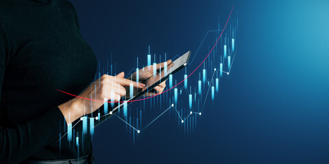 Wall Mural - Close up of female hands using tablet with glowing growing business chart on blurry background with mock up place. Financial growth and success concept.