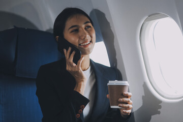 Young business woman sitting inside plane at the airport with sky view from the window drinking a cup of coffee