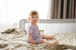 © Westend61 - Cute toddler girl sitting on bed at home