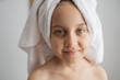© Westend61 - Smiling girl with towel wrapped on head after shower at home