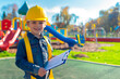© Rolando - Smiling Boy in Construction Hat with Clipboard at Playground