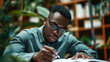 © OMD - A man wearing glasses and a shirt is focused on reading a book while sitting in a library surrounded by plants and bookshelves.