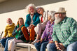 © Westend61 - Happy retired women and men sitting together on bench in front of wall