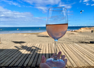 A glass of rose wine against a backdrop of beach, ocean and kitesurfing. A romantic end to the day