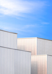 Group of industrial factory buildings with geometric pattern of aluminium corrugated metal wall against blue sky background in vertical frame