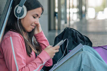 Wall Mural - teenager student girl with phone and headphones sitting on stairs