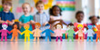 © MNStudio - Rainbow colored paper human figures holding their hands on kindergarten or school background. Diversity and inclusion concept.