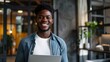 © Maryna - Male Office. Inspired African American Businessman Smiling at Camera in Modern Office with Laptop
