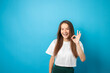 © yta - Teenager portrait on blue background, shows ok sign with fingers, young cute emotional student, smiling face with joyful emotion, fashionable curly hair