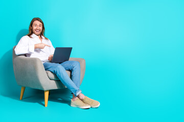 Canvas Print - Full length photo of cheerful positive guy dressed white shirt showing finger modern device emtpy space isolated turquoise color background