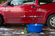 © ADDICTIVE STOCK - Manual car wash with red car, sudsy water, and cleaning supplies