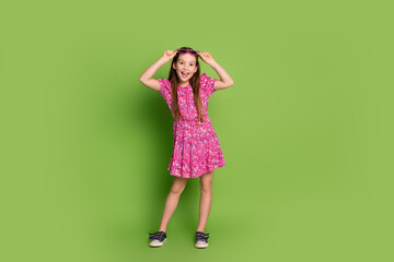 Wall Mural - Full body portrait of lovely schoolgirl cant believe empty space wear pink dress isolated on green color background