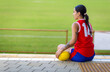 © Austockphoto - seen from behind one young lady football player seated on sidelines