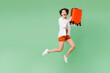 © ViDi Studio - Full body surprised excited shocked traveler woman wear casual clothes hold suitcase bag jump high isolated on plain green background. Tourist travel abroad in free time rest. Air flight trip concept.
