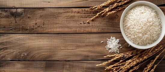 Poster - Rice plant and dried paddy rice in a white dish against a brown wooden background, providing ample copy space image.