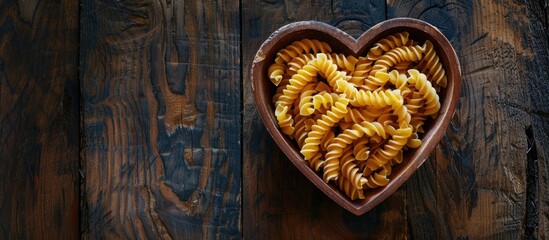 Aufkleber - Heart-shaped wooden box filled with pasta or raw macaroni against a dark wooden backdrop, with space for additional text or images. Illustrating a healthy vegetarian diet emphasizing carbohydrates.