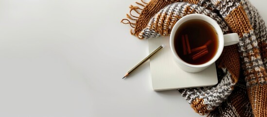 Aufkleber - White ceramic cup of coffee, a knitted plaid, notebook, and pencil are displayed on a white surface with space for additional images.