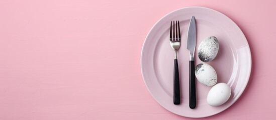 Aufkleber - Top view of Easter dinner setting featuring black and white eggs, knife, and fork on a pastel pink background with ample copy space for text.
