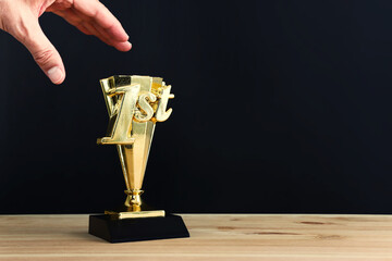 Wall Mural - golden trophy on wooden table and dark background. idea of award and success
