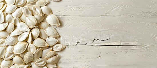 Aufkleber - A pile of pumpkin seeds positioned to the left of a copy space image on a pale wooden background.
