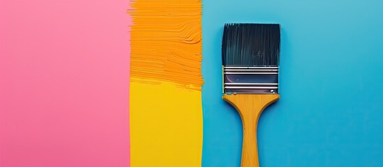 Poster - Top view of a paintbrush placed on a vibrant blue, pink, and yellow background perfect for a colourful wallpaper with copy space image.