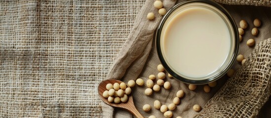 Poster - Glass of soy milk with a spoonful of soybeans on a rustic sackcloth background, perfect for adding your text with copy space image.