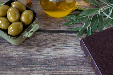 Wall Mural - Holy bible book, olives, oil, and green branch on rustic wooden table. Top view.  Christian biblical concept of anointing, healing, symbol of God's Holy Spirit.