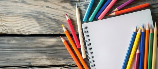 Fototapete - Wooden table with an empty notebook and colorful pencils, providing copy space image.