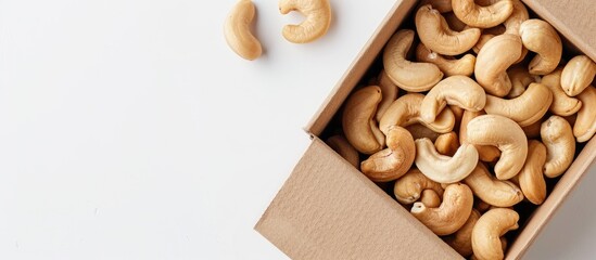 Poster - An image showcasing a close-up of a cashew nut in a brown box on a white background, emphasizing the healthy food concept and allowing for text to be added in the available space.