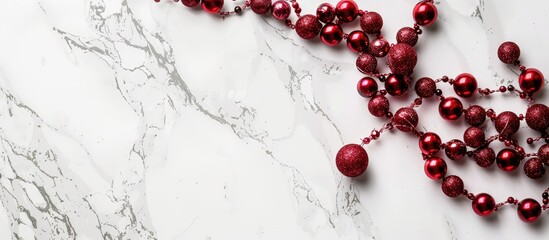 Poster - A festive Christmas frame featuring a string of red beads on a sleek marble background, viewed from above with room for text or images.